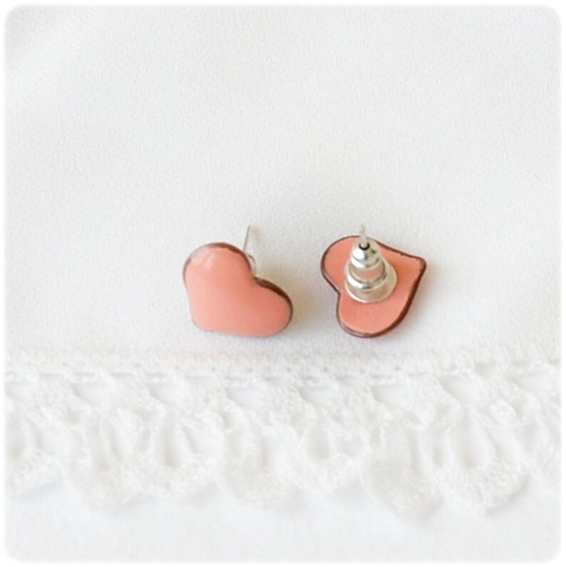 May include: A pair of pink heart-shaped stud earrings with silver posts.