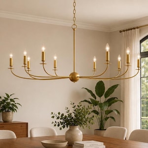 Può includere: Un lampadario lineare con finitura in oro spazzolato dotato di dodici luci a candela disposte su bracci curvi. L'apparecchio è sospeso tramite una catena centrale e include un elemento centrale sferico con sottili bracci in metallo.