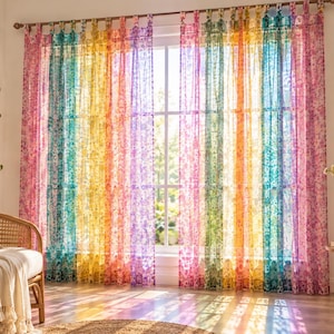 May include: Sheer window curtains featuring vertical stripes in a rainbow colour palette of pink, orange, yellow, green, and blue. The fabric has a delicate floral pattern throughout and is hung from a rod using fabric loops at the top edge.
