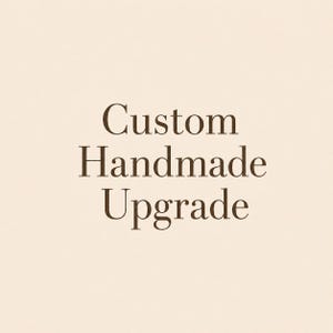 May include: A square graphic featuring a light beige background with the dark brown text Custom Handmade Upgrade centered in the middle. The font is a classic serif style with clear, legible lettering that stands out against the neutral backdrop.