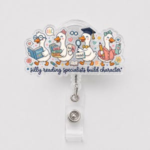 May include: A clear acrylic badge reel featuring a colorful illustration of four white ducks engaged in reading activities. The text reads, "silly reading specialists build character." The ducks are depicted with books, a pencil, and a graduation cap.