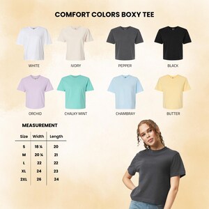 May include: A collection of Comfort Colors boxy t-shirts in white, ivory, pepper, black, orchid, chalky mint, chambray, and butter. A measurement chart lists widths and lengths in inches for sizes S through 2XL. A person wears a pepper-colored tee.