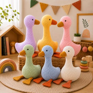Op de afbeelding: Een verzameling van zes gehaakte eendjes in verschillende pastelkleuren, waaronder lavendel, geel, roze, lichtgroen, lichtblauw en crème. Elke eend heeft een lichaam van textuurgaren, een donkerbruine snavel en kleine zwarte kraaloogjes.