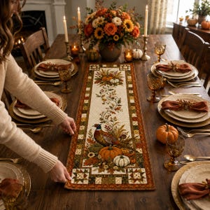 A person is setting the table for a meal, with a table runner featuring a seasonal design and autumn decorations.