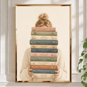 May include: A stack of twelve hardcover books with floral and celestial gold foil details on the spines, held by a person wearing a cream-colored cable knit sweater. The titles include Pride and Prejudice, Little Women, Anne of Green Gables, The Secret Garden, The Hobbit, The Book Thief, A Little Life, The Invisible Life, Sense and Sensibility, Persuasion, Wuthering Heights, and Jane Eyre.