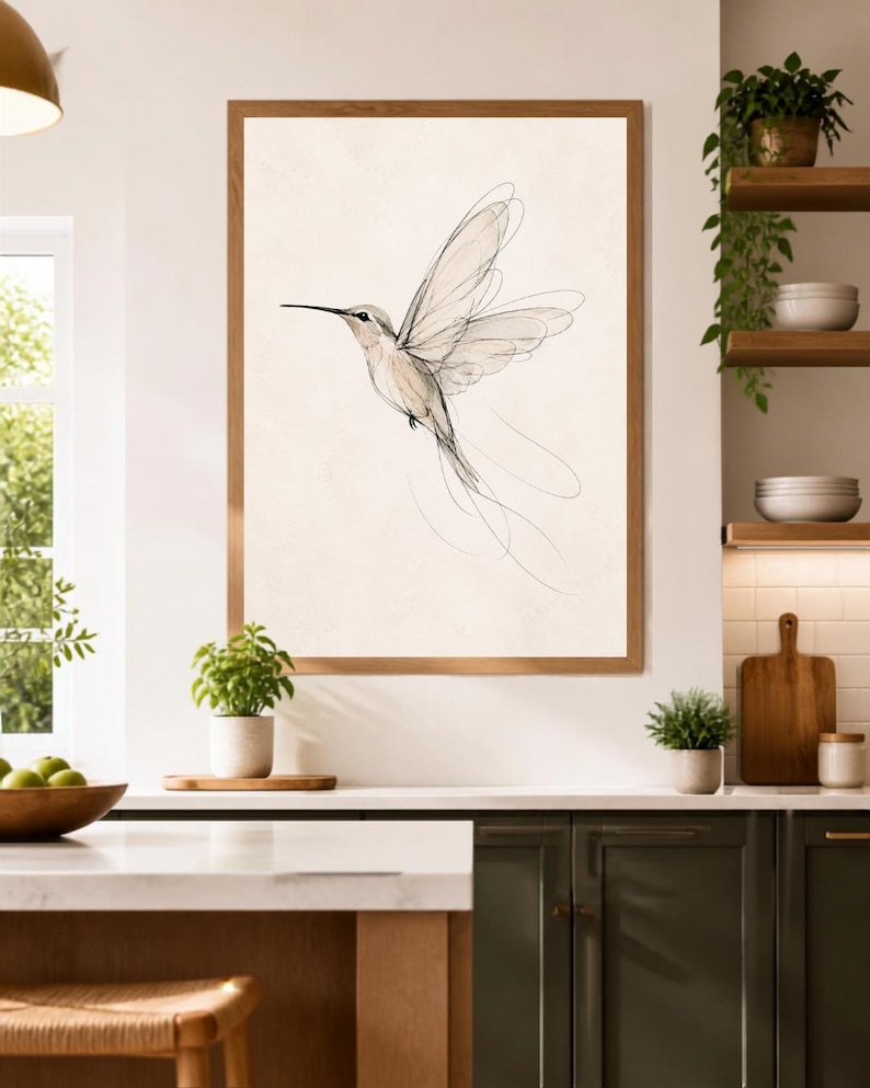 May include: A framed wall art print featuring a delicate, minimalist line drawing of a hummingbird in flight. The artwork uses fine black ink strokes on a light cream background, capturing the bird's wings and long tail feathers in motion.
