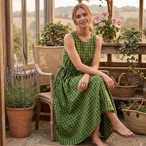 May include: A sleeveless midi dress featuring a green and black checkered pattern, a round neckline, and a side tie detail at the waist. The dress is constructed with a fitted bodice that transitions into a full, flowing skirt that falls below the knee.