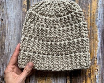May include: A beige crocheted beanie hat with a textured stitch pattern.