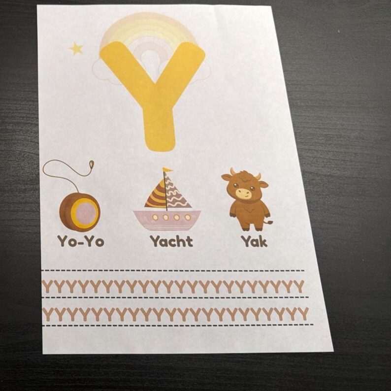 Op de afbeelding: Een wit educatief blad met een grote gele letter Y met een regenboog op de achtergrond. Daaronder staan illustraties van een bruine jojo, een zeilboot met het label Yacht en een bruine jak. Onderaan staan twee rijen van de letter Y in bruin.