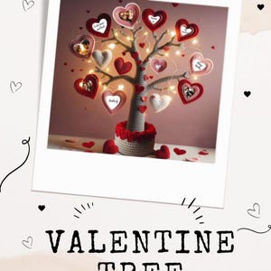 Op de afbeelding: Een gehaakte boom met een grijze stam en voet, versierd met rode en witte hartvormige ornamenten. Sommige harten bevatten kleine ronde foto's. De boom is verlicht met dunne lichtsnoeren. De tekst VALENTINE TREE staat eronder.