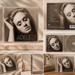 May include: A CD case featuring Adele's album "21". The cover art is a sepia-toned portrait of Adele. The album title is displayed in a clean, sans-serif font. The back of the case shows the tracklist and a photo of Adele.