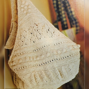May include: A close-up of a beige crocheted bag with a detailed pattern. The bag is hanging on a wall and the text "Vintage 00, Advanced Pattern" is visible at the bottom of the image.