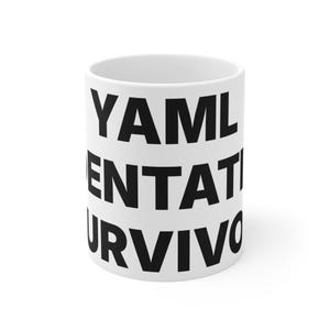 May include: A white ceramic mug featuring bold black text printed on the side. The text reads YAML, ENTAT, and URVIVO in stacked capital letters. The mug has a cylindrical shape with a smooth finish and a standard handle on the side.