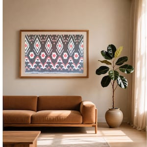 Könnte beinhalten: Ein rechteckiges Wandbild aus dunkelgrauem Stoff mit einem sich wiederholenden geometrischen Ikat-Muster in Weiß und Rot. Das Design besteht aus Rautenformen und stilisierten Blumenmotiven, die in horizontalen Reihen in einem Holzrahmen angeordnet sind.