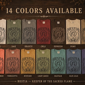 May include: A display of 14 different colored t-shirts, each featuring a graphic of a woman with a halo and the word "HESTIA". The shirts are labeled with colors like white, sage, and blue jean. Text at the bottom reads "HESTIA - KEEPER OF THE SACRED FLAME".