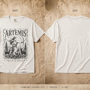 May include: White t-shirt featuring a black graphic of Artemis, the Greek goddess of the hunt, with a bow and arrow, surrounded by deer and trees. The word "ARTEMIS" is above the image. The back of the shirt is plain white.