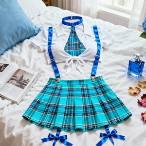 Op de afbeelding: Een wit kortemouwen crop-top met kraag en strikdetail aan de voorzijde, gecombineerd met een turquoise en blauwe geruite plooirok. De set bevat een bijpassende geruite stropdas met blauwe kraag, blauwe bretels en twee blauwe strikjes aan de zoom.