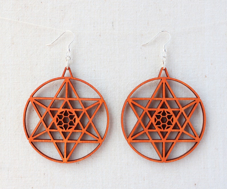 May include: A pair of wooden earrings with a geometric design. The earrings are orange-brown in colour and have a silver hook.