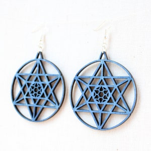 May include: A pair of blue wooden earrings with a geometric star design. The earrings are round and have a silver hook.