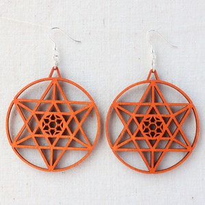 May include: A pair of wooden earrings with a geometric star design. The earrings are orange and have a silver hook.