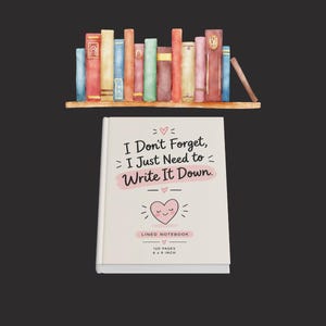 Può includere: Un quaderno a righe bianco con un'illustrazione di un cuore rosa e il testo I Don't Forget, I Just Need to Write It Down, 120 pagine, 15,24 x 22,86 cm. Sopra c'è una mensola in legno con una fila di libri colorati.