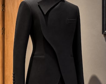 May include: A black blazer on a mannequin featuring a high standing collar with an asymmetrical overlapping front closure, long sleeves with four buttons at the cuffs, and a single welt pocket on the chest. The text ELITE STUDIO ATTIRE USA is visible.
