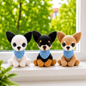 Puede incluir: Tres figuras de chihuahua tejidas a ganchillo sentadas en fila. La de la izquierda es blanca con orejas negras, la del medio es negra y marrón, y la de la derecha es marrón. Cada figura tiene grandes ojos negros y un pañuelo azul claro tejido.