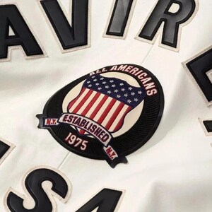 May include: White jacket with black lettering and patches. The jacket features a patch with a shield design, the American flag, and the text "ALL AMERICANS ESTABLISHED 1975 N.Y."