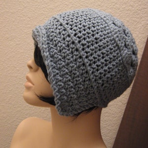 May include: A pale blue crochet hat with a turned-up brim. The hat is crafted from textured yarn, featuring a close-knit design. The hat is shown on a mannequin head.
