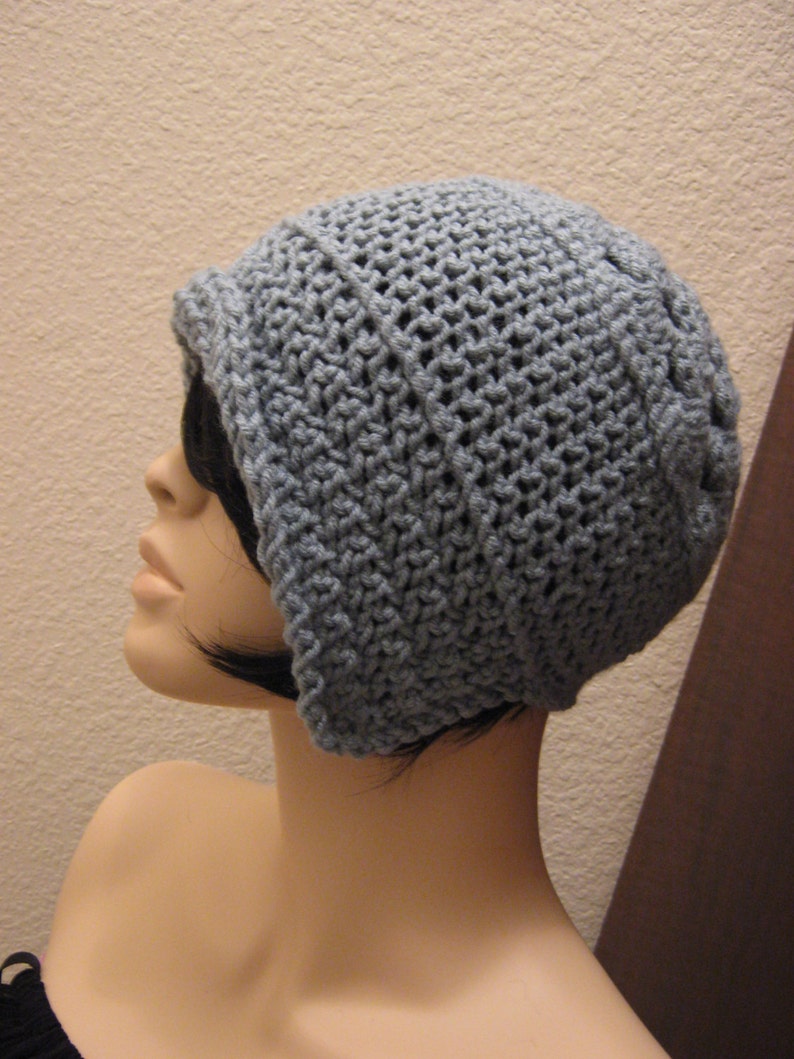 May include: A pale blue crochet hat with a turned-up brim. The hat is crafted from textured yarn, featuring a close-knit design. The hat is shown on a mannequin head.