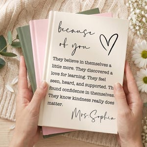 May include: A stack of three hardcover books with a cream-coloured front cover featuring the black text "because of you" with a heart icon, followed by a paragraph about self-belief and learning, ending with the signature "Mrs. Sophia".