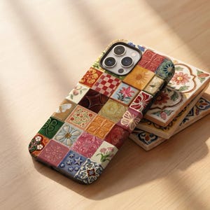 Puede incluir: Una funda para smartphone con un diseño de patchwork multicolor de baldosas cuadradas con varios motivos florales, geométricos y de mariposas en tonos rojos, azules, amarillos, verdes y rosas, sobre una pila de baldosas de cerámica a juego.