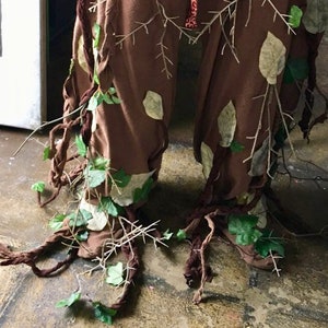 May include: Brown pants with vines, leaves, and branches attached to them. The pants are made to look like a tree trunk.