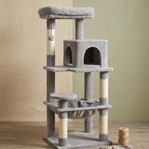 May include: A multi-level cat tree featuring soft gray plush fabric, several vertical support posts wrapped in light beige sisal rope, a square enclosed cubby, a top platform, and a suspended fabric hammock for resting and climbing.