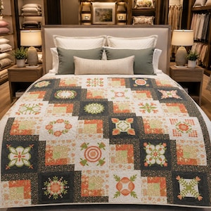May include: A bed quilt featuring a patchwork design of alternating square blocks in shades of charcoal gray, burnt orange, and cream. The pattern includes intricate floral and geometric motifs, with a textured surface and stitched detailing throughout.