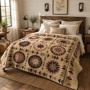 Könnte beinhalten: Eine Tagesdecke mit einem sich wiederholenden Muster aus großen kreisförmigen Sternmotiven in den Farben Dunkelpflaume, Salbeigrün und Creme. Die Decke ist mit kleinen dreieckigen Formen in ähnlichen Farben auf hellem Cremegrund verziert.