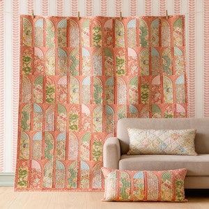 May include: A large rectangular quilt and a matching rectangular throw pillow featuring a repeating pattern of arched windows. The fabric displays floral prints in shades of coral, sage green, and cream, with quilted vertical lines.