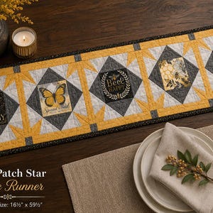 May include: A rectangular quilted table runner featuring a Nine Patch Star pattern in yellow, gray, and white. The fabric panels display bee-themed graphics and text including Bee Kind, Spread Your Wings, Bee Happy, and Kind Words Change Lives.