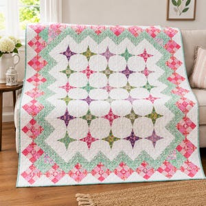 May include: A rectangular quilt featuring a central white field with a repeating star pattern in shades of pink, purple, and green. The border consists of a zigzagging green floral print and a diamond-patterned edge in various shades of pink.