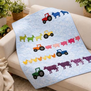 Pode incluir: Uma manta acolchoada para bebé em azul claro com motivos de quinta bordados, incluindo tratores vermelhos, amarelos, laranja, azuis e verdes, juntamente com filas de ovelhas, cabras, porcos, galinhas e vacas de várias cores.
