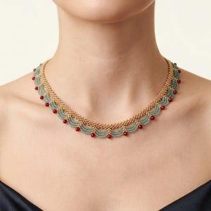 May include: A beaded necklace featuring a scalloped design made of small gold-toned beads and light sage green beads. The lower edge of the necklace is accented with evenly spaced, small, round, deep red beads along the entire length.