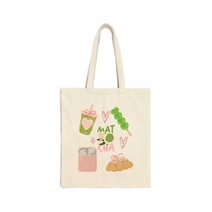 Könnte beinhalten: Cremefarbene Tragetasche mit Matcha-Illustrationen. Das Design umfasst ein Matcha-Getränk mit Herz, das Wort "MATCHA", einen Spieß mit Dango, einen Matcha-Ball, ein rosa Etui mit Ohrhörern und ein Croissant.