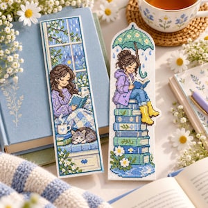 May include: Two rectangular cross-stitch bookmarks. The left bookmark shows a person reading by a window with a cat and a mug. The right bookmark features a person sitting on a stack of books under a green umbrella, reading a book.