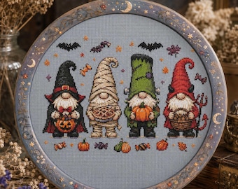 May include: A circular embroidery hoop containing a cross-stitch pattern of four Halloween gnomes on a light blue fabric. The gnomes are dressed as a vampire, a mummy, a monster, and a devil, surrounded by small pumpkins, bats, and candy icons.