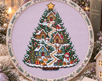 Può includere: Un telaio da ricamo circolare contenente un disegno a punto croce di un grande albero di Natale su tessuto viola chiaro. L'albero presenta casette, pupazzi di neve, una renna, una volpe e regali incartati, sormontato da una stella gialla.