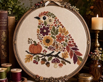May include: A circular cross-stitch embroidery featuring a bird composed of autumn-colored flowers, leaves, and berries. The bird sits on a branch with a small orange pumpkin and mushrooms. The piece is framed in an ornate bronze-toned hoop.