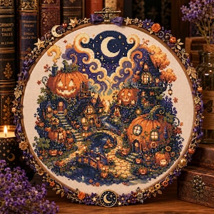 May include: A circular embroidery hoop containing a cross-stitch pattern of a nighttime scene with orange jack-o'-lantern houses, a winding stone path, and a crescent moon in a dark blue sky. The wooden hoop is decorated with metal stars and flowers.