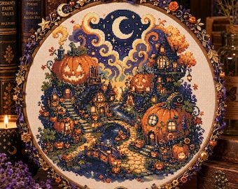 May include: A circular embroidery hoop containing a cross-stitch pattern of a nighttime scene with orange jack-o'-lantern houses, a winding stone path, and a crescent moon in a dark blue sky. The wooden hoop is decorated with metal stars and flowers.