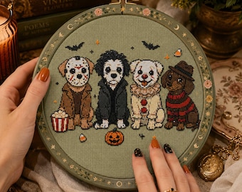May include: A circular embroidery hoop containing a cross-stitch design on sage green fabric. The design features four dogs dressed as horror movie characters: Jason Voorhees, a dark-haired figure, Pennywise, and Freddy Krueger, with a pumpkin.