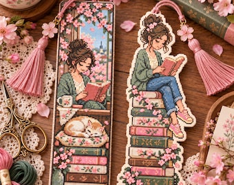 May include: Two rectangular bookmarks featuring cross-stitch designs of a person reading books. One bookmark is a solid rectangle, the other is die-cut to the shape of the stack of books. Both feature pink tassels with cherry blossom charms.